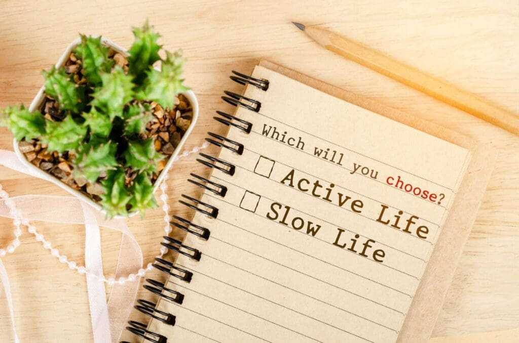 What’s Your Life’s Purpose? 1 Whick will you Choose? Active life or Slow life in notebook with cactus on wooden background. Conceptual between active life and slow life
