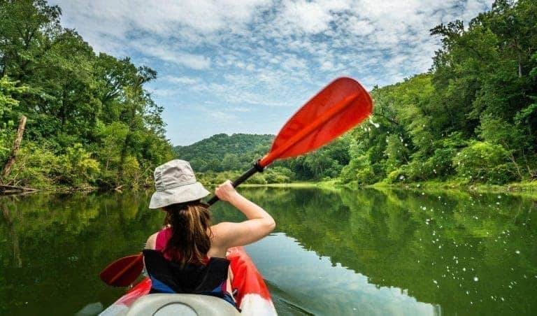 A woman paddling in Buffalo River while kayaking in Arkansas.