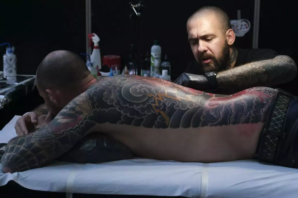 Tattoo artist tattooing a man