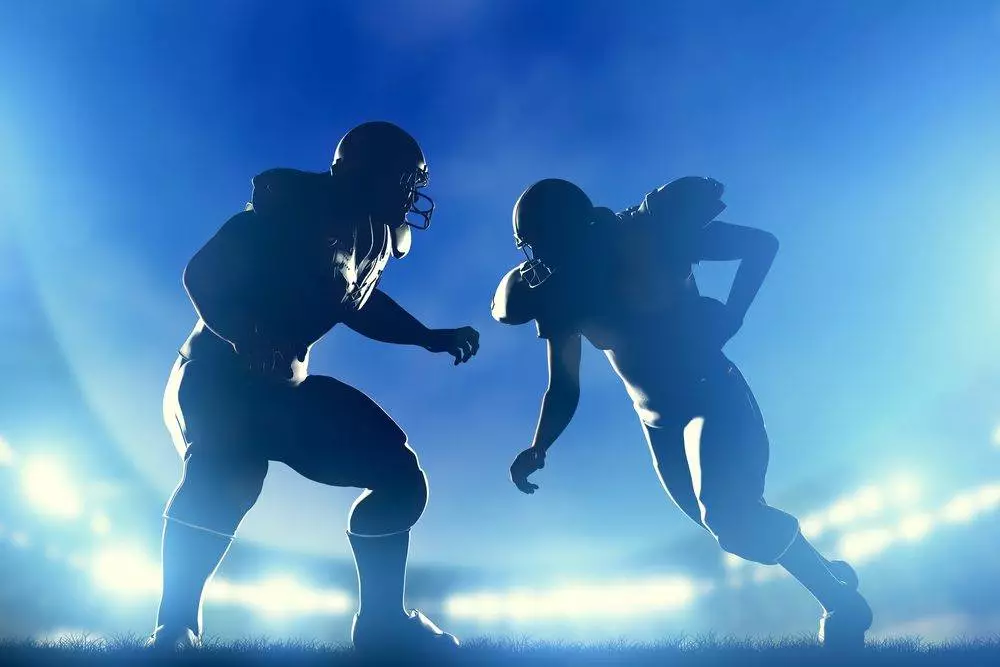 American football players in game, quarterback running. Night stadium lights.