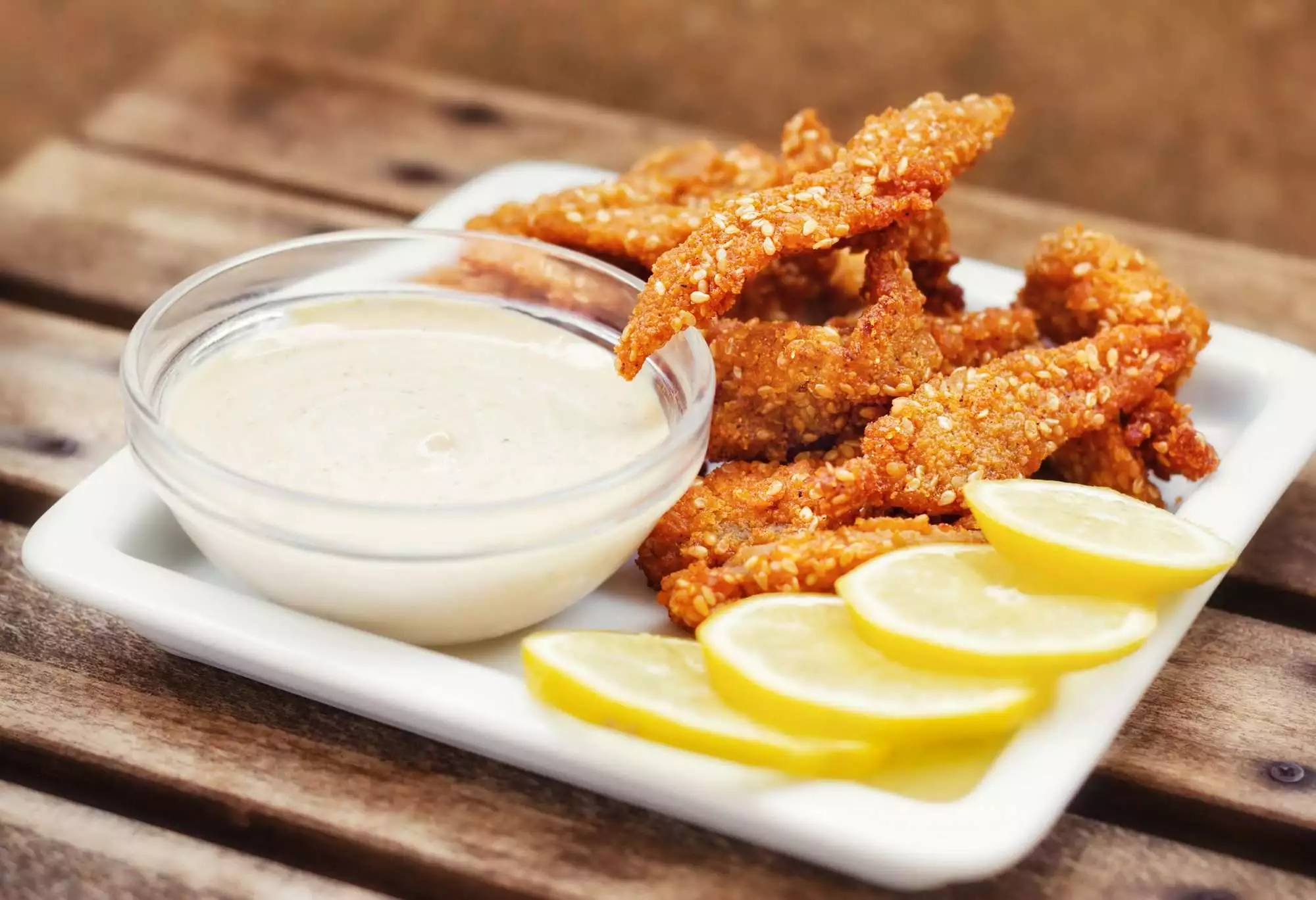 Chicken fingers served with tartar sauce and lemon slice